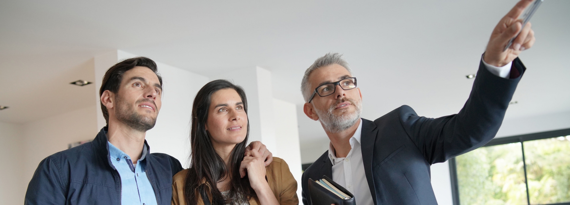 Een man en vrouw bezichtigen een woning samen met een mannelijke makelaar
