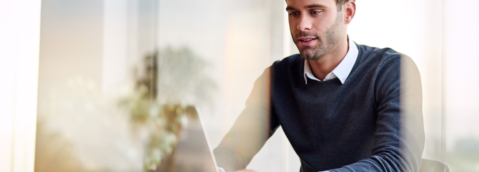 Jonge ondernemer is vanuit huis aan het werk op zijn laptop